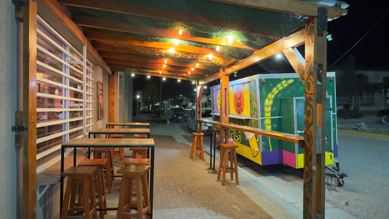 Mesas afuera de Barfly de noche con luces y el trailer